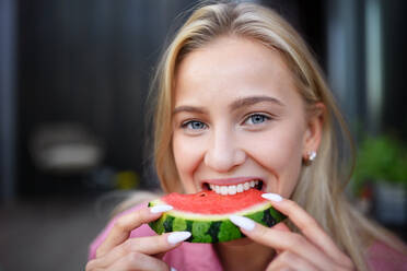Ein Porträt einer schönen jungen Frau, die eine Wassermelone isst und in die Kamera schaut. - HPIF05029