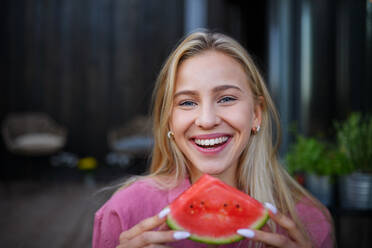 Ein Porträt einer schönen jungen Frau, die eine Wassermelone isst und in die Kamera schaut. - HPIF05030