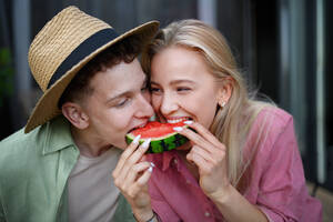 Ein fröhliches, verliebtes junges Paar isst gemeinsam ein Stück Wassermelone - HPIF05031