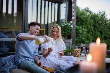 A young couple clinking with wine outdoors, weekend away in tiny house in countryside, sustainable living. - HPIF05050