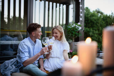 A young couple clinking with wine outdoors, weekend away in tiny house in countryside, sustainable living. - HPIF05051