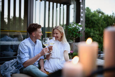 Ein junges Paar stößt im Freien mit Wein an, ein Wochenende in einem kleinen Haus auf dem Land, nachhaltiges Leben. - HPIF05051