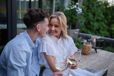 A young couple clinking with wine outdoors, weekend away in tiny house in countryside, sustainable living. - HPIF05052