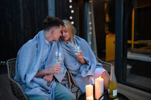 Ein junges Paar mit Wein, das sich abends auf der Terrasse ausruht, Wochenende in einem kleinen Haus auf dem Land, nachhaltiges Leben. - HPIF05063