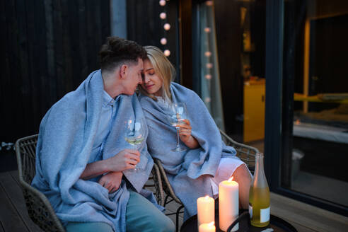 Ein junges Paar mit Wein, das sich abends auf der Terrasse ausruht, Wochenende in einem kleinen Haus auf dem Land, nachhaltiges Leben. - HPIF05063