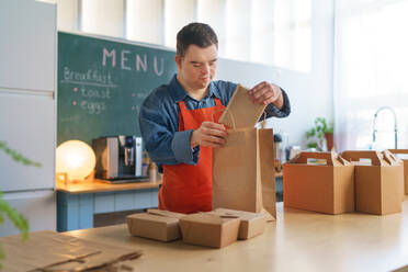 A cheerful young Down Syndrome waiter working in take away restaurant, social inclusion concept. - HPIF05073