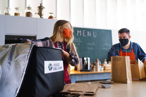 A courier taking meals for delivery from waiter with Down syndrome. Social inclusion concept. - HPIF05086