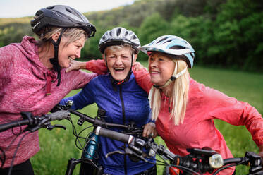 Glückliche, aktive Seniorinnen, die gemeinsam draußen in der Natur Rad fahren. - HPIF05133