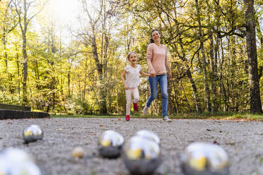 Glückliches Mädchen und Mutter spielen mit Boule im Park - DIGF19669