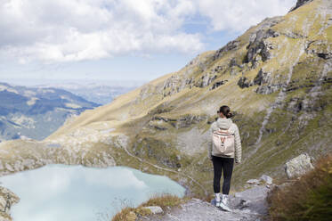 Wanderer mit Rucksack steht auf einem Felsen und schaut auf einen Berg - MEF00143