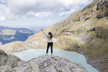 Young hiker with arms raised standing on rock - MEF00144