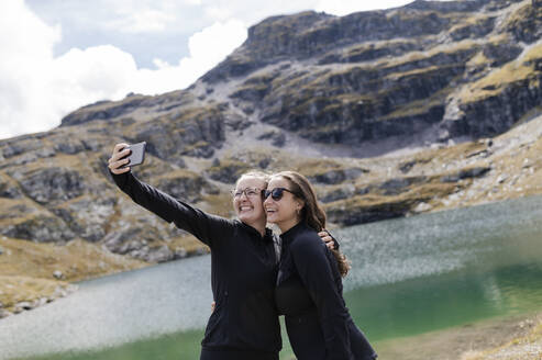 Glückliche Wanderer machen ein Selfie mit ihrem Smartphone in der Nähe eines Sees - MEF00150