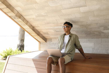 Smiling freelancer with laptop on bench - SYEF00078