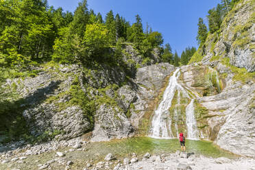 Germany, Bavaria, Female hiker admiring Glasbachwasserfall in summer - FOF13254