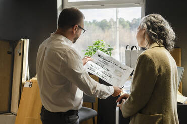 Zwei Kollegen arbeiten in einem Architekturbüro an einem Bauplan - SEAF01523