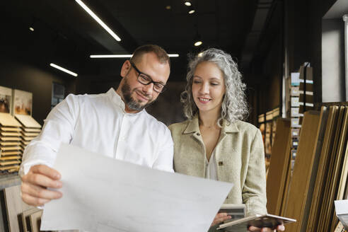 Two confident colleagues holding plan in architect's office - SEAF01544