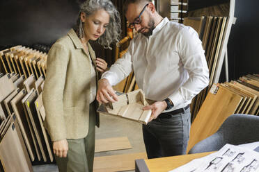 Zwei Kollegen arbeiten in einem Architekturbüro gemeinsam an einem Holzmodell - SEAF01547