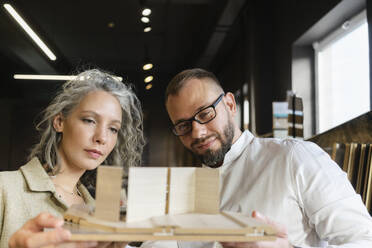 Two colleagues working on wooden model in architect's office together - SEAF01548