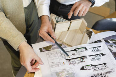 Close-up of two colleagues working on blueprint in architect's office together - SEAF01553