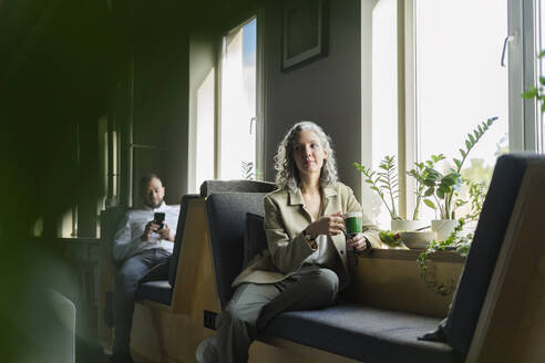 Geschäftsfrau macht eine Pause im Büro und sitzt am Fenster - SEAF01576