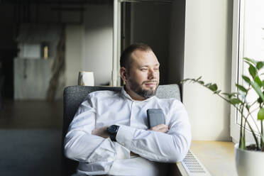 Geschäftsmann, der eine Pause im Büro macht und aus dem Fenster schaut - SEAF01577