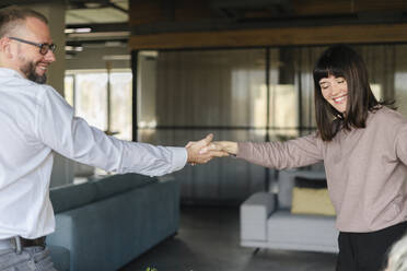 Glücklicher Geschäftsmann und Frau beim Händeschütteln im Büro - SEAF01603