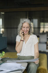 Architect on the phone working on plan in office lounge - SEAF01616