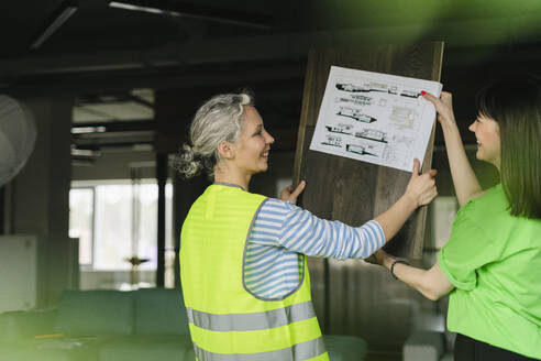 Frau und Ingenieurin halten gemeinsam einen Bauplan im Büro - SEAF01667