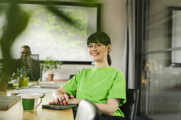 Portrait of smiling woman wearing green t-shirt during a meeting in conference room - SEAF01691