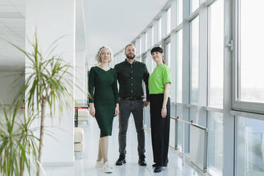 Drei Geschäftsleute in grüner Kleidung stehen auf dem Boden eines Büros - SEAF01725