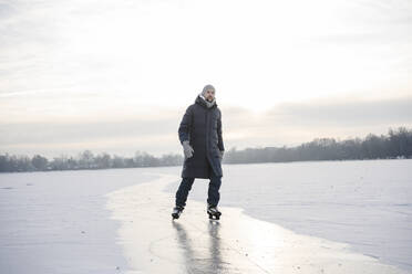 Mann beim Schlittschuhlaufen auf zugefrorenem See im Winter - EYAF02407