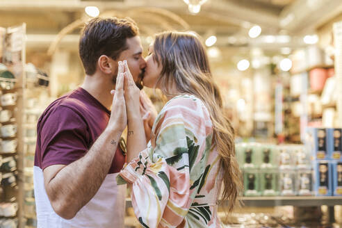 Zärtlicher Mann und Frau küssen sich im Geschäft - LJF02372