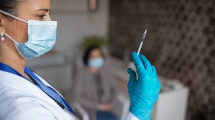 A portrait of woman doctor with syringe standing in hospital, coronavirus concept. - HPIF05138