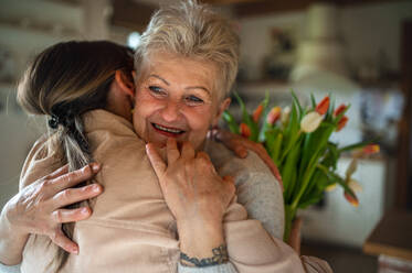 Eine glückliche ältere Mutter umarmt erwachsene Tochter drinnen zu Hause, Muttertag oder Geburtstagsfeier. - HPIF05169