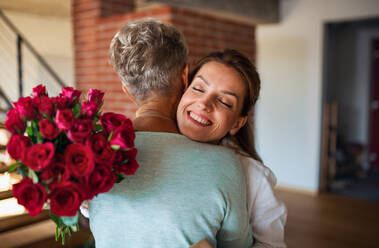 A happy senior mother hugging adult daughter indoors at home, mothers day or birthday celebration. - HPIF05247