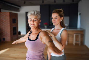 Eine aktive ältere Frau in Sportkleidung trainiert mit einer Physiotherapeutin zu Hause. - HPIF05259