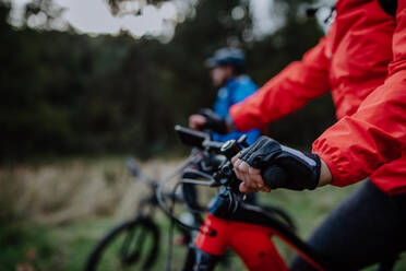 A detail of senior woman's hand riding bikes outdoors with her husband in forest in autumn day. - HPIF05311