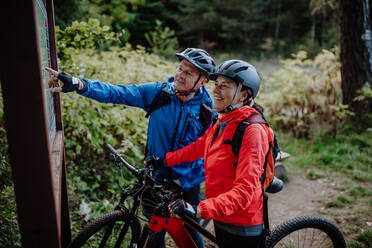 Ein glückliches älteres Paar Radfahrer ruht im Freien in der Natur im Herbst Tag. - HPIF05317