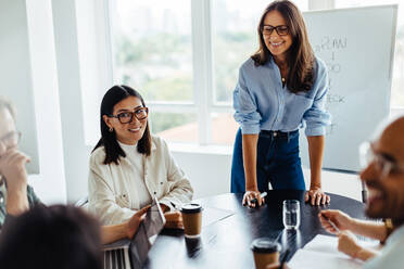 Woman discussing her ideas with her team in a meeting. Business woman giving a presentation to a group of business people in an office. - JLPSF28666