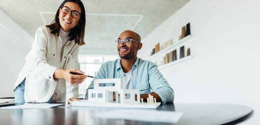 Kreative Designer, die in einem Büro an einem 3D-Hausmodell arbeiten. Junge Geschäftsleute, die ein neues Architekturprojekt planen. - JLPSF28696