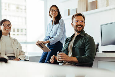 Professionals listening to a discussion in an office. Group of happy business people having a team meeting. - JLPSF28726