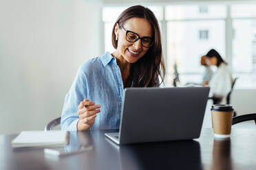 Woman having an online business meeting while sitting in an office. Business woman discussing a new project with her clients on a video call. - JLPSF28736