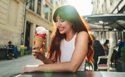 Close-up of young woman holding melting eating ice cream cone in