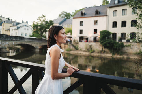 Frau, die auf einer Sightseeing-Reise in Europa die Aussicht von einer Brücke aus betrachtet. Weibliche Touristin, die im Urlaub neue Orte erkundet. Bei diesem Foto wurde absichtlich das Korn eines 35-mm-Films verwendet. - JLPPF01582