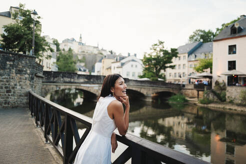 Frau genießt eine Sightseeing-Tour in Luxemburg-Stadt. Glückliche Reisende, die auf einer Brücke stehend die Aussicht genießt. Dieses Foto hat absichtlich 35mm Filmkorn verwendet. - JLPPF01584