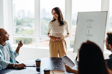 Eine Geschäftsfrau diskutiert mit ihrem Team in einer Vorstandssitzung. Eine Geschäftsfrau präsentiert ihre Strategie in einem Büro. - JLPSF28759