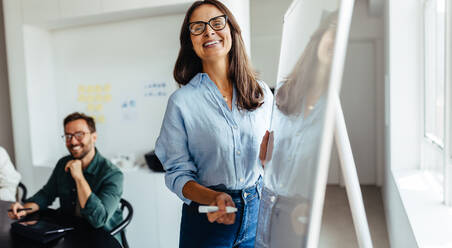 Reife Geschäftsfrau, die eine Sitzung in einem Büro leitet. Kreative Geschäftsfrau, die einem Team von Designern in einem Sitzungssaal eine Präsentation gibt. - JLPSF28763