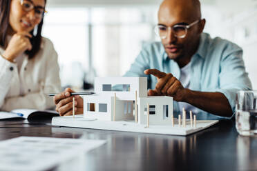 Männlicher Architekt bespricht ein 3D-Hausmodell mit seinem Kollegen in einem Büro. Kreative Geschäftsleute arbeiten an einem neuen Bauprojekt. - JLPSF28771
