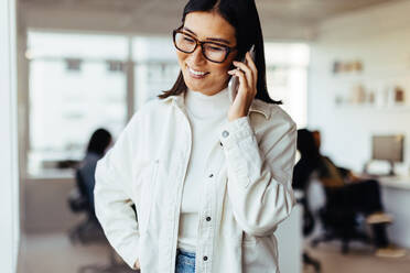 Eine Geschäftsfrau telefoniert an ihrem Arbeitsplatz. Eine Frau spricht mit ihren Geschäftspartnern am Telefon in einem Büro. - JLPSF28800