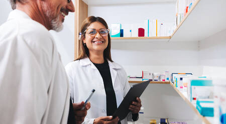 Two pharmacists doing a stock take using a tablet in a drug store. Happy healthcare professionals working together in a pharmacy. - JLPSF28950